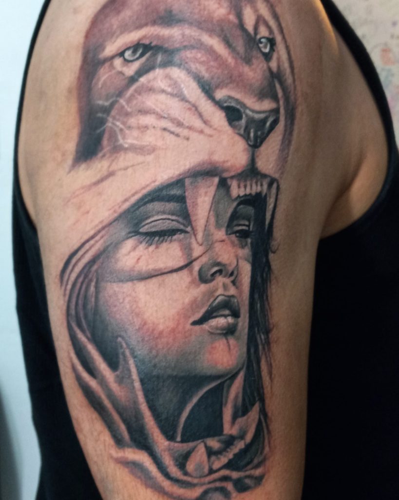 Black-and-grey portrait tattoo of a woman beneath a snarling big cat on upper arm