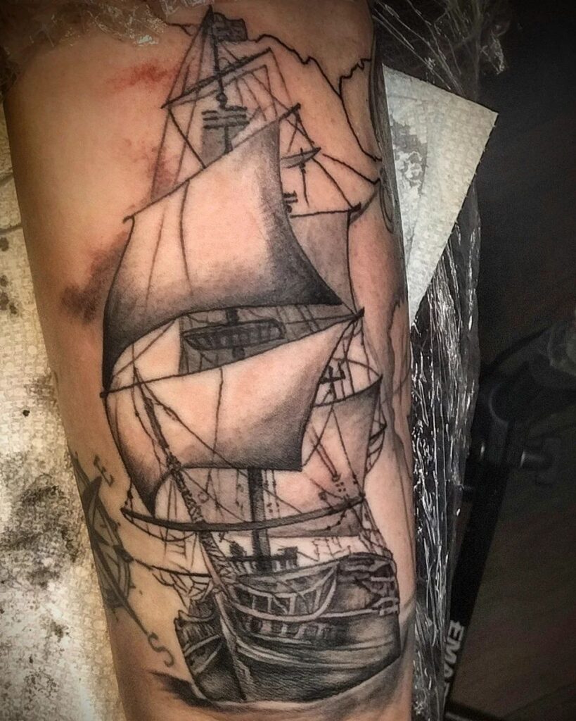 Black-and-grey sailing ship tattoo on the upper arm